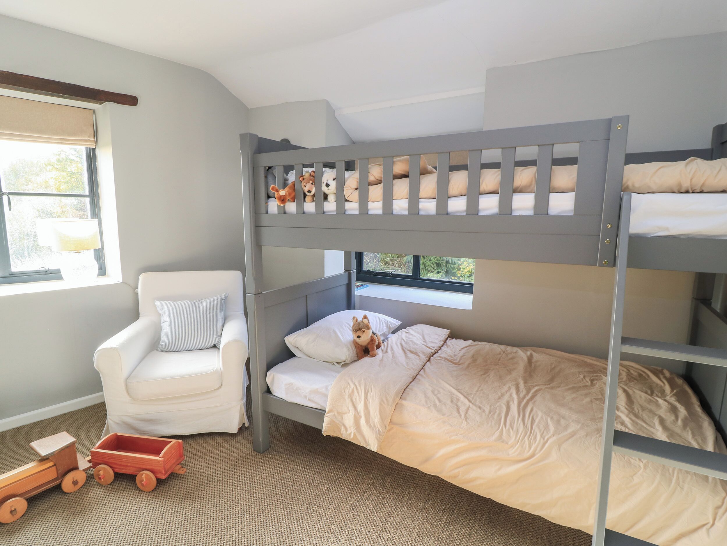 Habitación con literas, una silla blanca y un tren de juguete.