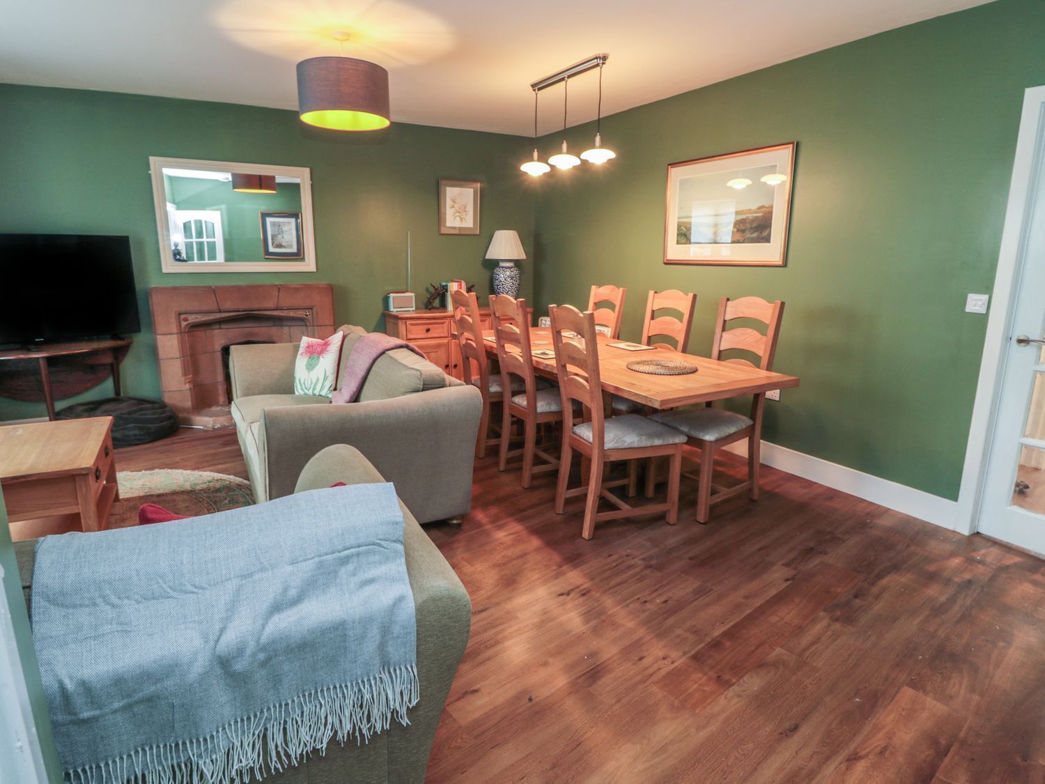 A living room with a TV, sofa, and dining table with chairs.