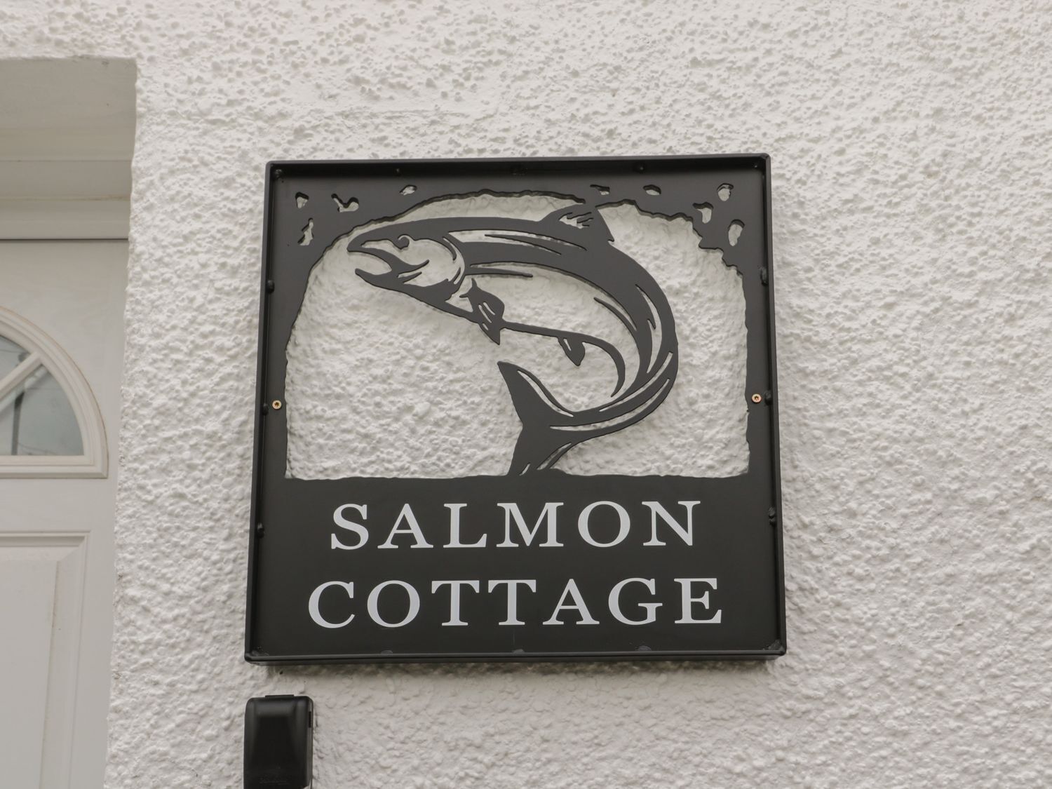 A sign for 'Salmon Cottage' with a stylized salmon graphic.