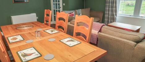 A dining area with a wooden table, chairs, and a sofa.