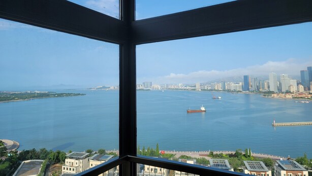 A view from a high-rise window overlooking a large body of water with a city skyline in the distance.