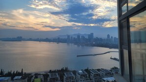 A high-rise building with a view of a city skyline across a body of water.