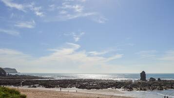 A beach with rocky terrain and a clear sky.