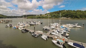 A marina with various boats docked, a wooden pier, and a backdrop of hills and trees. - 22 Dart Marina (Dartmouth)