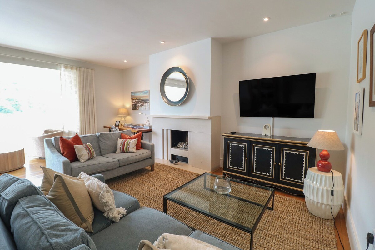 A living room with a sofa, a coffee table, a fireplace, a television, and a cabinet.