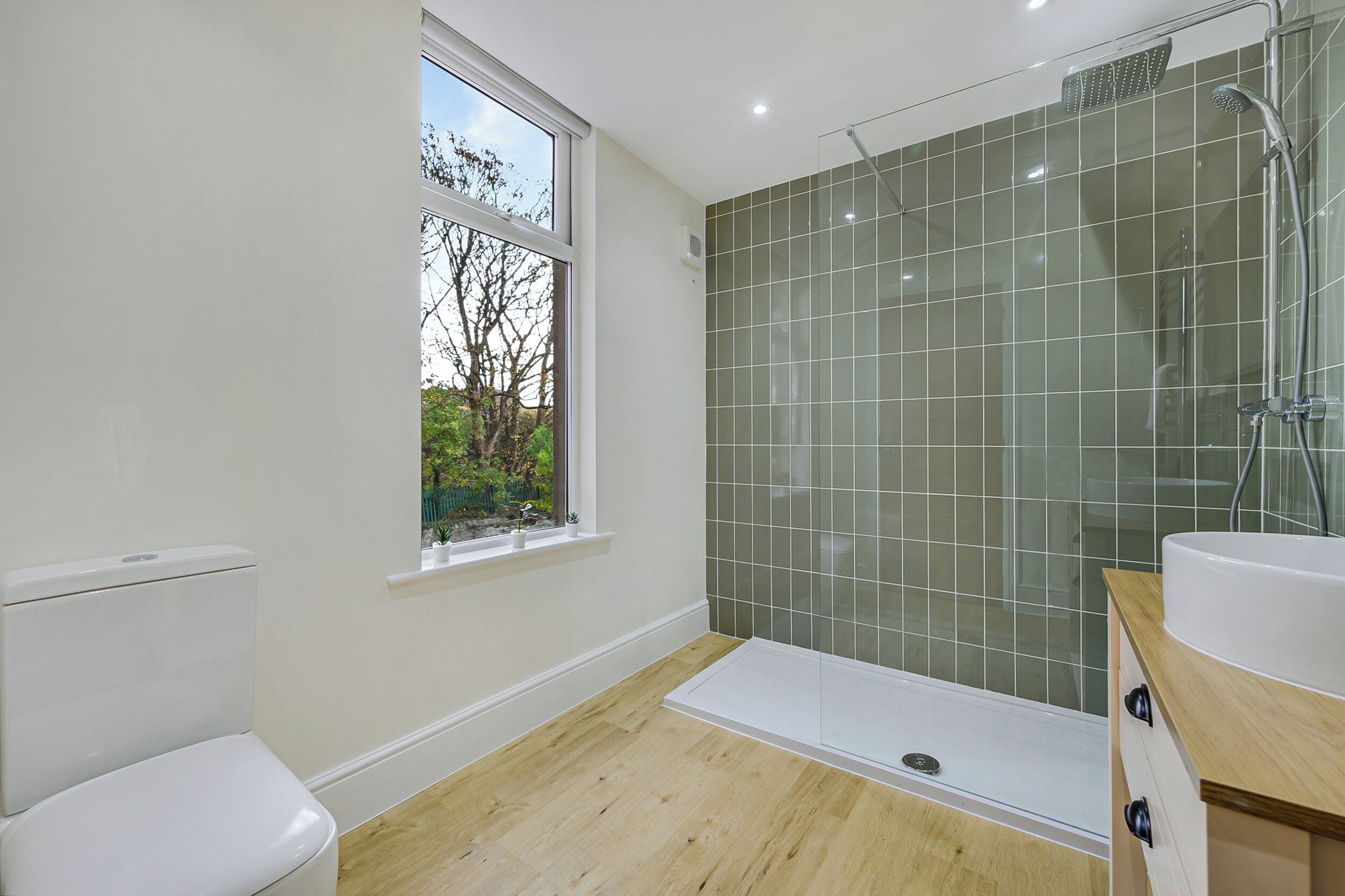 A modern bathroom with a toilet, a shower, and a sink.