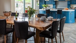A modern kitchen with blue cabinets, a central island, and a dining area with a wooden table and black chairs.