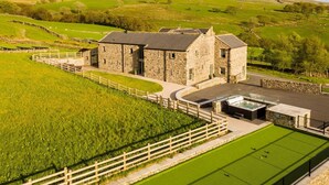 A stone building with a pool and a green lawn.