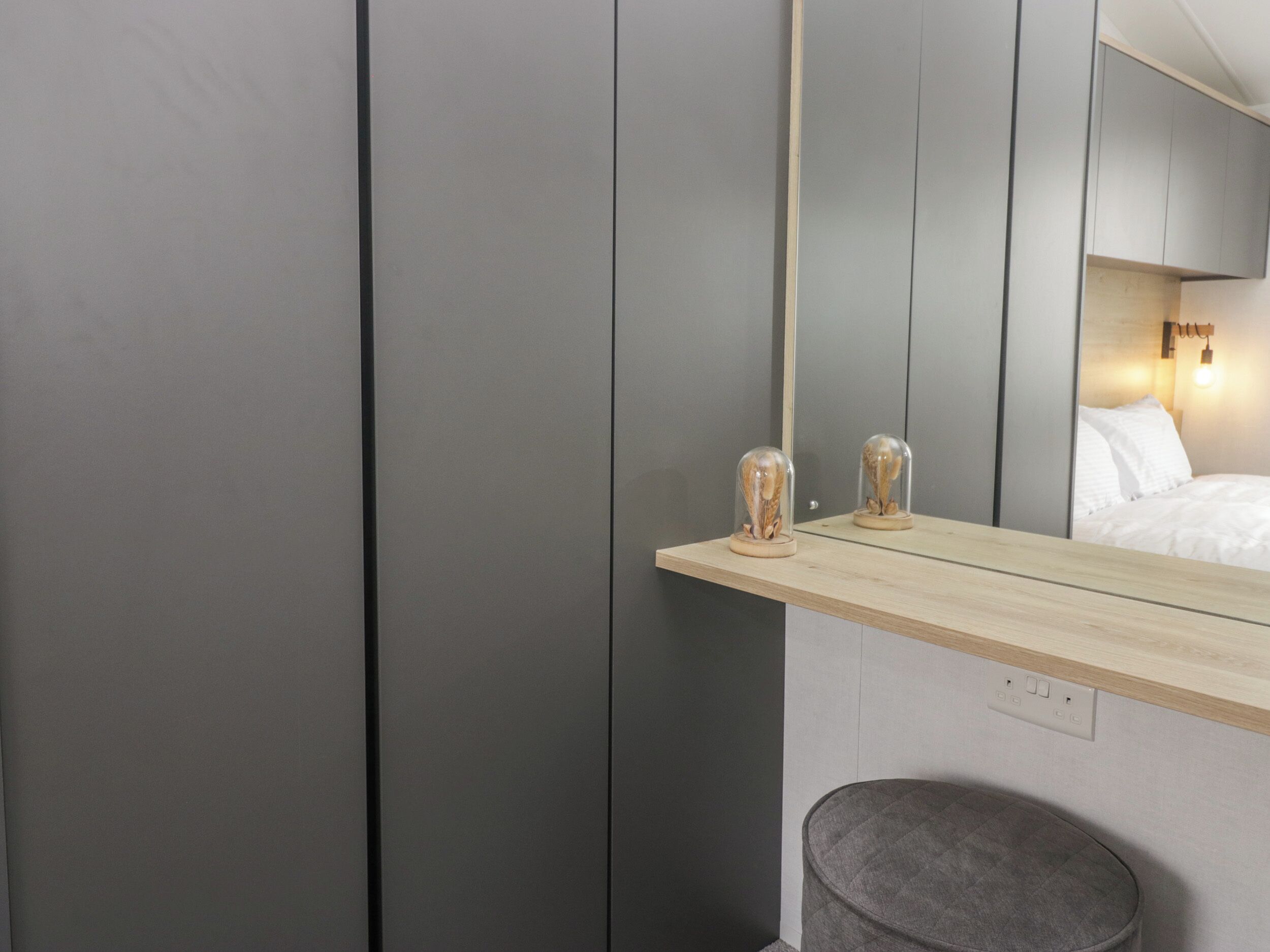 A modern bathroom with a wooden vanity, a mirror, and a round stool.