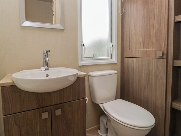 Une salle de bain avec un lavabo blanc, des toilettes et des meubles en bois.
