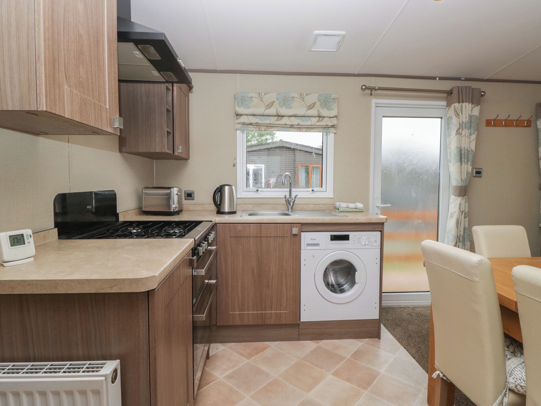 A compact kitchen with a stove, toaster, sink, and washing machine.