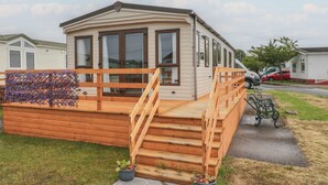 Ein Wohnmobil mit Holzterrasse, einer Rampe und Kübelpflanzen.