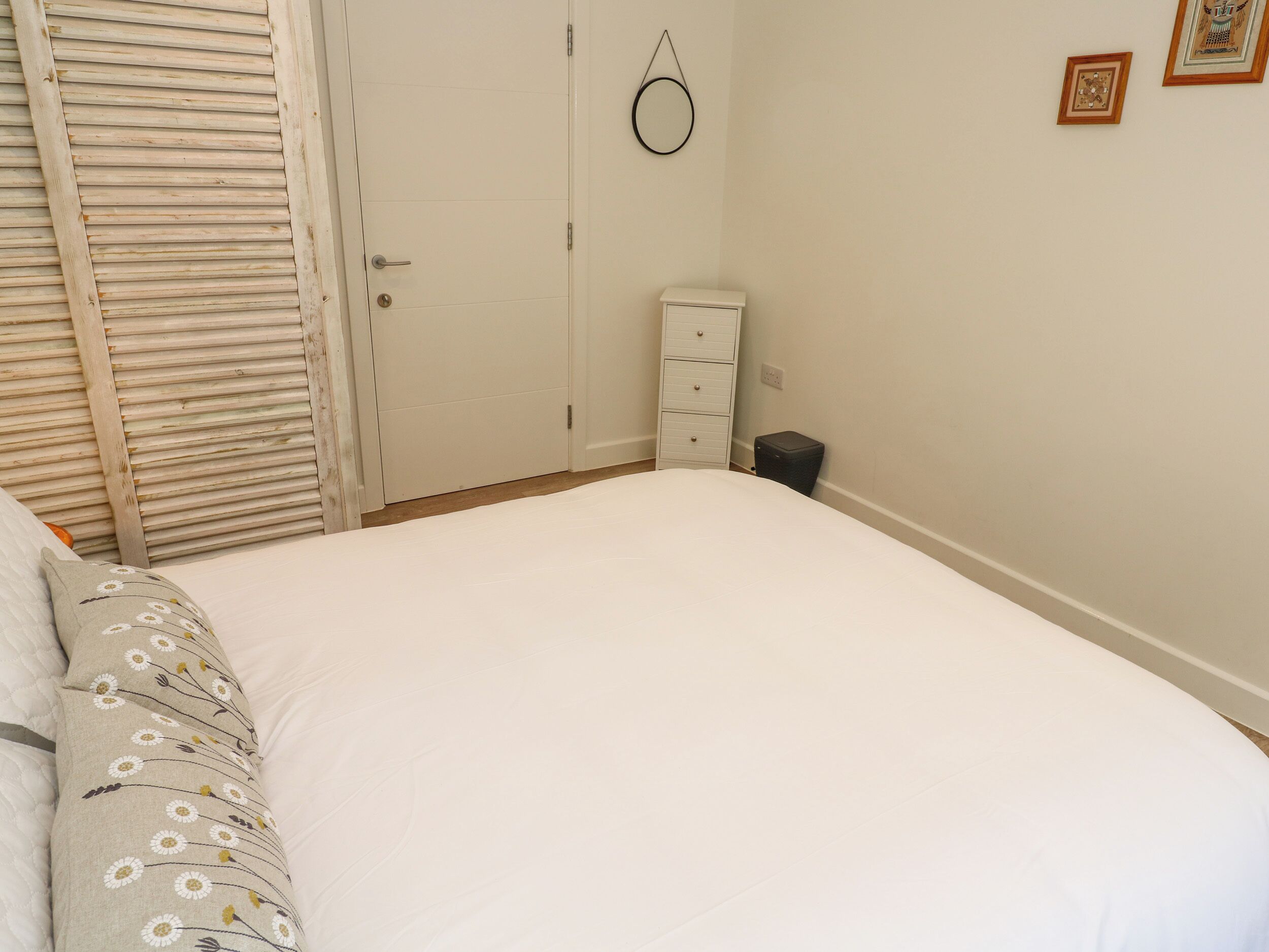 Ein Schlafzimmer mit einem Bett, einem Kleiderschrank, einer Kommode und einem Papierkorb.