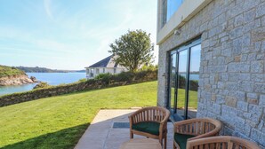 A patio with wooden furniture and a stone wall. - 2 The Dunes (Falmouth)