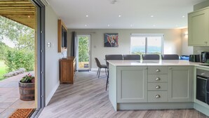 A modern kitchen with a large island, built-in appliances, and a view of the outdoors. - Orchard Lodge (Corwen)