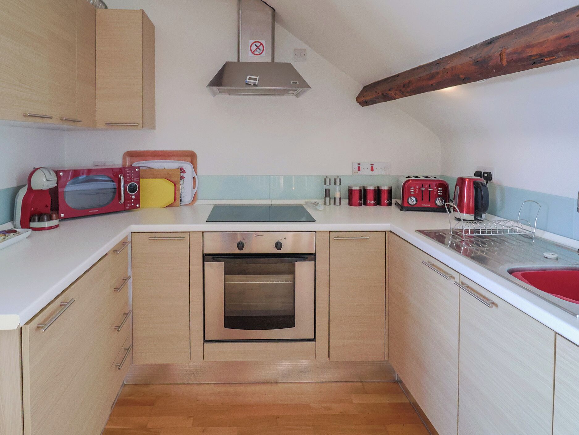 Una cocina compacta con armarios de madera, horno empotrado, microondas y tostadora.