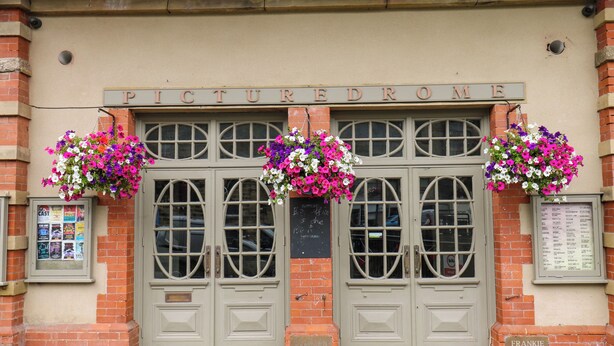 A building with a sign reading "PICTURED DROME" and two hanging flower baskets. - Valley View Cottage (Holmfirth)