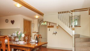 A dining area with a wooden table and chairs, a staircase, and a kitchen in the background. - Sherway Shippen (Exeter)