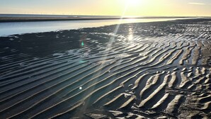 A beach with wet sand patterns and a clear sky. - Jacob's Retreat (Skegness)