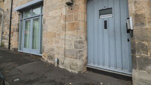 A stone building with a blue door labeled "Tomlinsons Apartments." - The Coquet Nest (Morpeth)