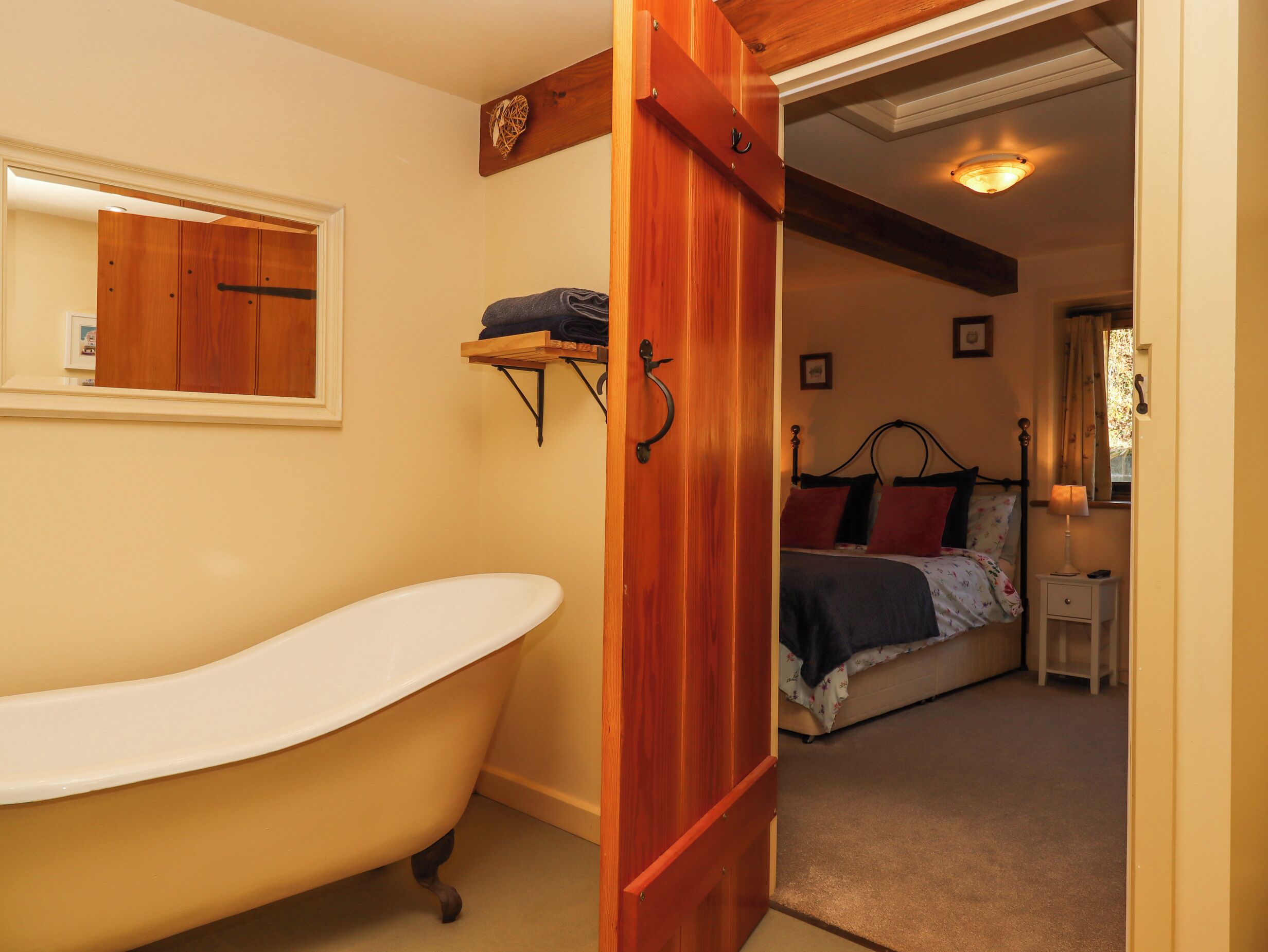 Ein Badezimmer mit freistehender Badewanne, einer Holztür und einem Regal mit Handtüchern.