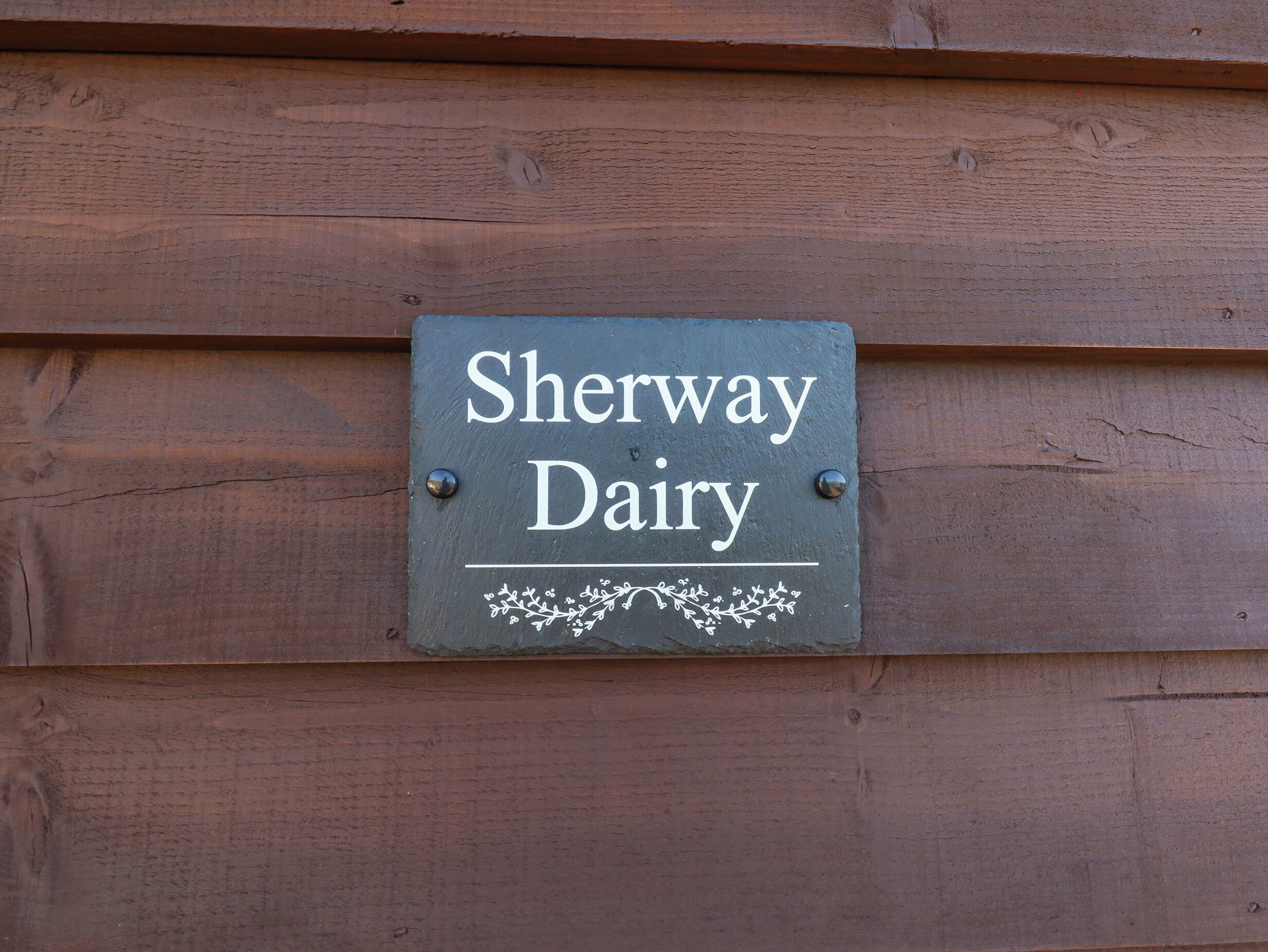 A sign reading "Sherway Dairy" mounted on a wooden wall.