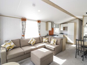 Una sala moderna con un sofá, un reposapiés y un comedor con mesa y sillas.
