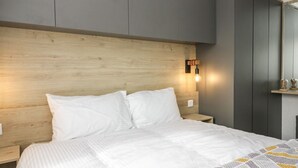 Une chambre à coucher moderne avec une tête de lit en bois, un lit avec une literie blanche et une table de chevet.