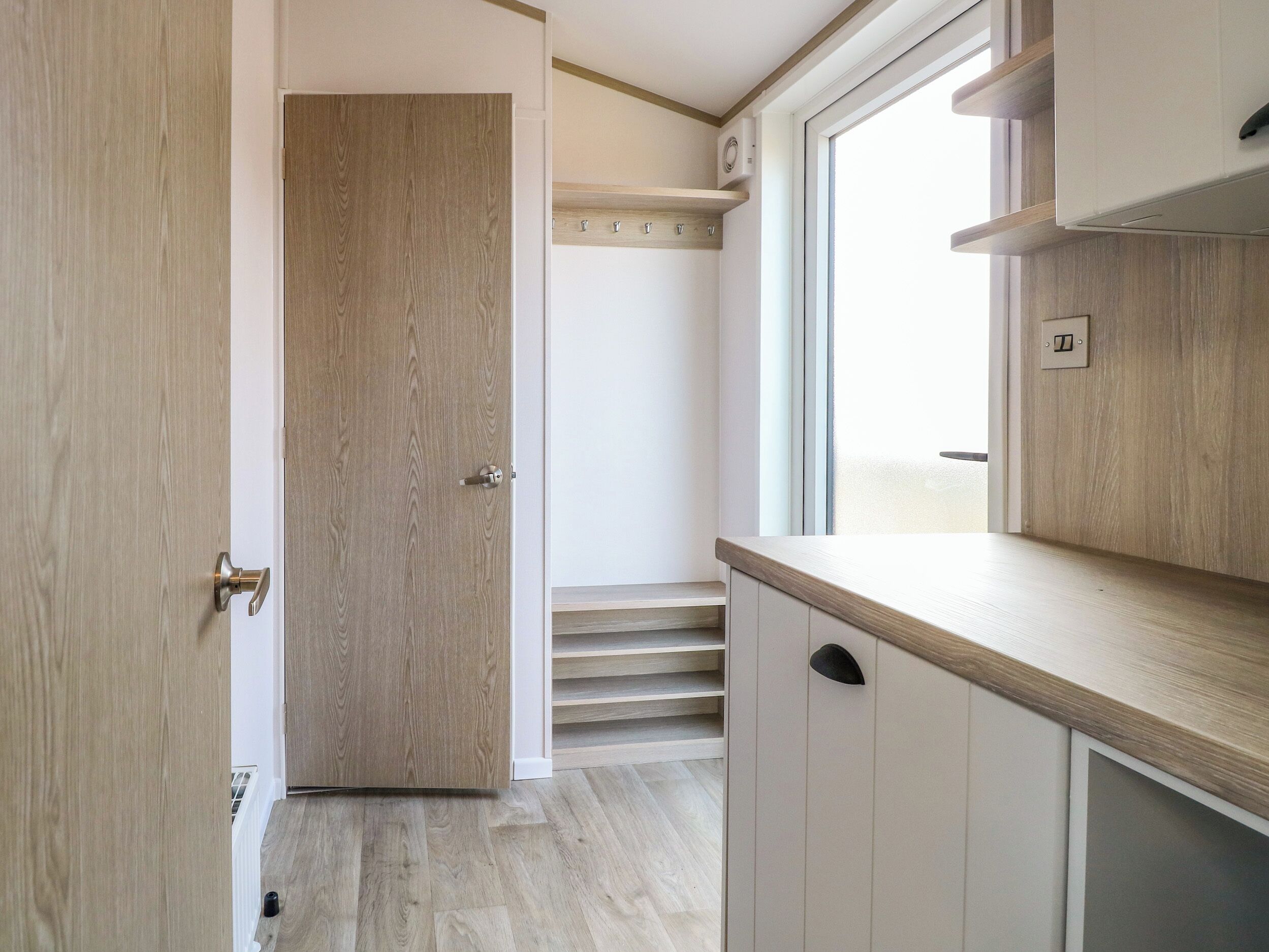 Eine moderne Küche mit Holzausstattung, einem Backofen und einem Fenster über der Spüle.