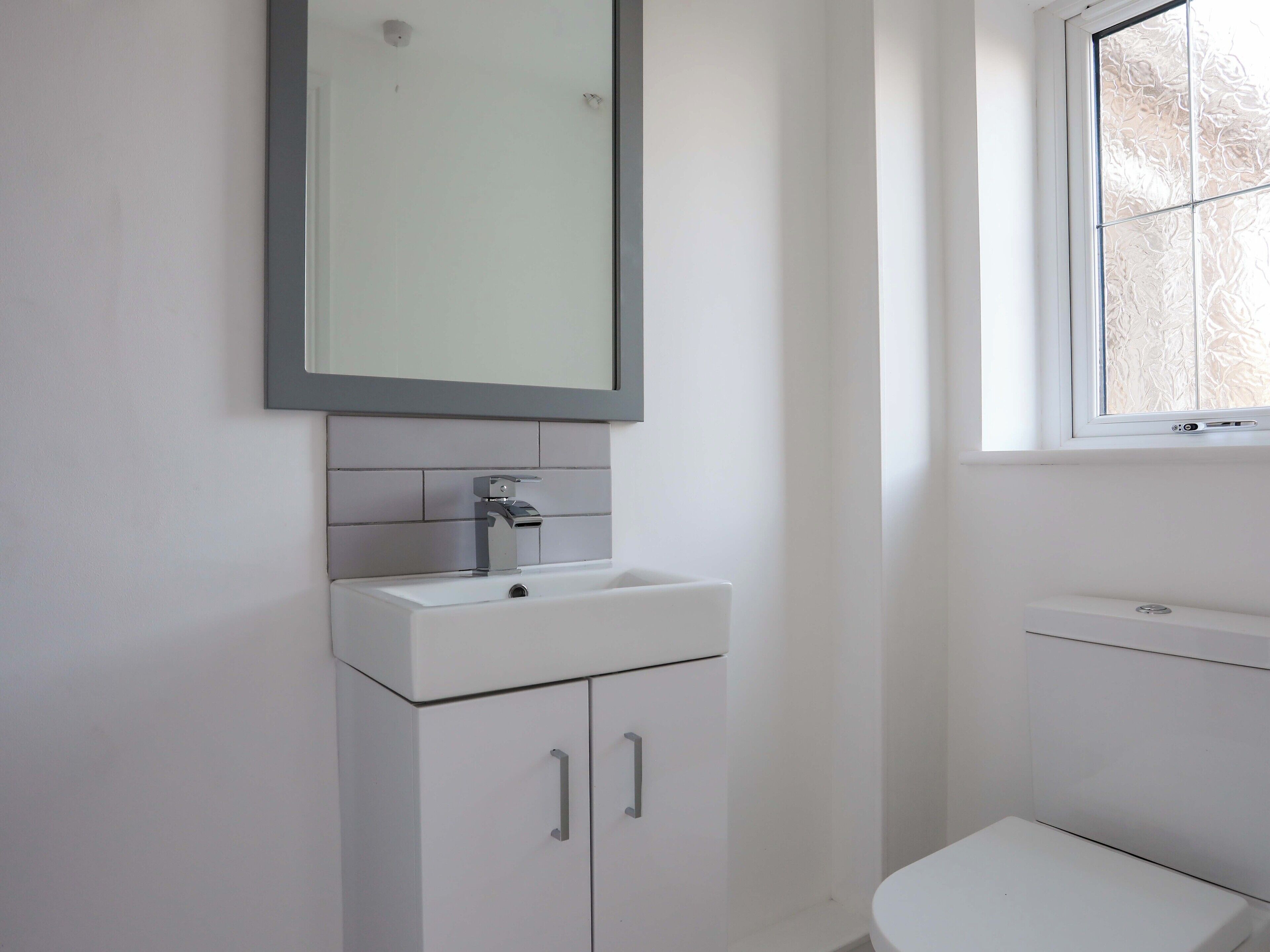 Ein Badezimmer mit Waschbecken, Spiegel und Toilette.