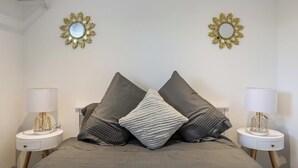 A bedroom with a bed, two bedside tables, two lamps, and two wall mirrors. - Ty'n Ffridd Bach (Pwllheli)