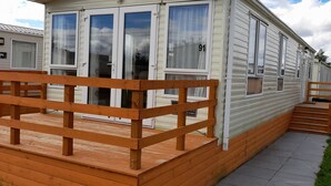 Ein Mobilheim mit Holzterrasse und der Nummer 91 am Fenster.