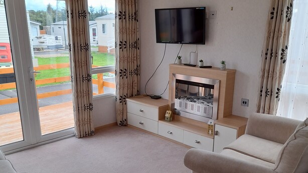 Ein Wohnzimmer mit Flachbildfernseher an der Wand, Kamin und zwei Sofas.