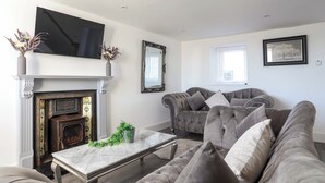 Una sala de estar con chimenea, un sofá, un televisor y un espejo enmarcado.