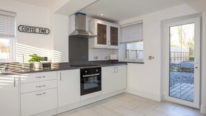 Una cocina moderna con armarios blancos, una campana extractora de acero inoxidable y un horno empotrado.