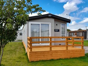 A mobile home with a wooden deck and a 'For Sale' sign. - Yew (Denny)