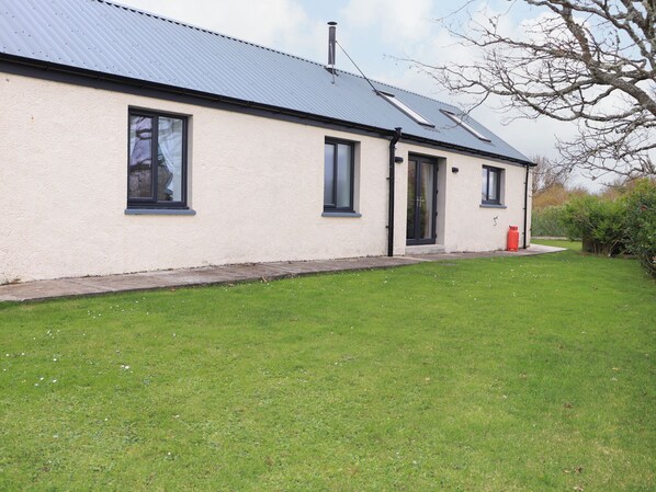 A single-story building with a flat roof, large windows, and a grassy lawn. - Bayview Byre (Isle of Lewis)