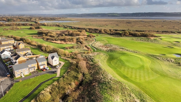 Un campo de golf con un club house, un estanque y edificios residenciales.