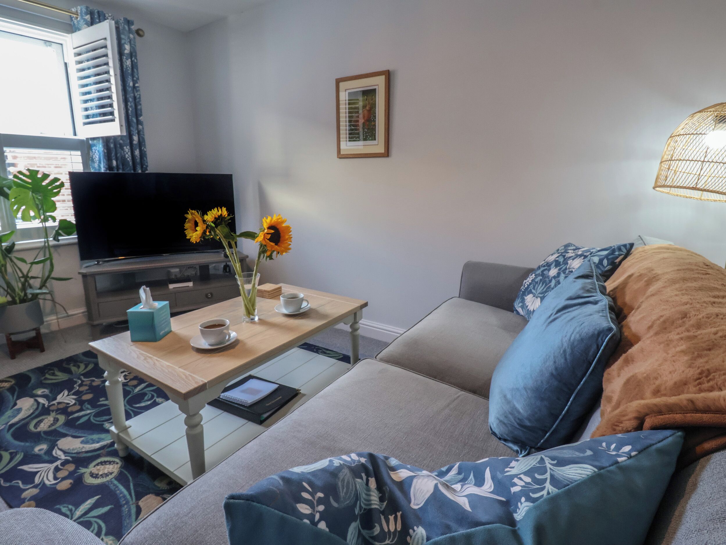 Una sala de estar con sofá, una mesa de centro, televisor y planta en maceta.