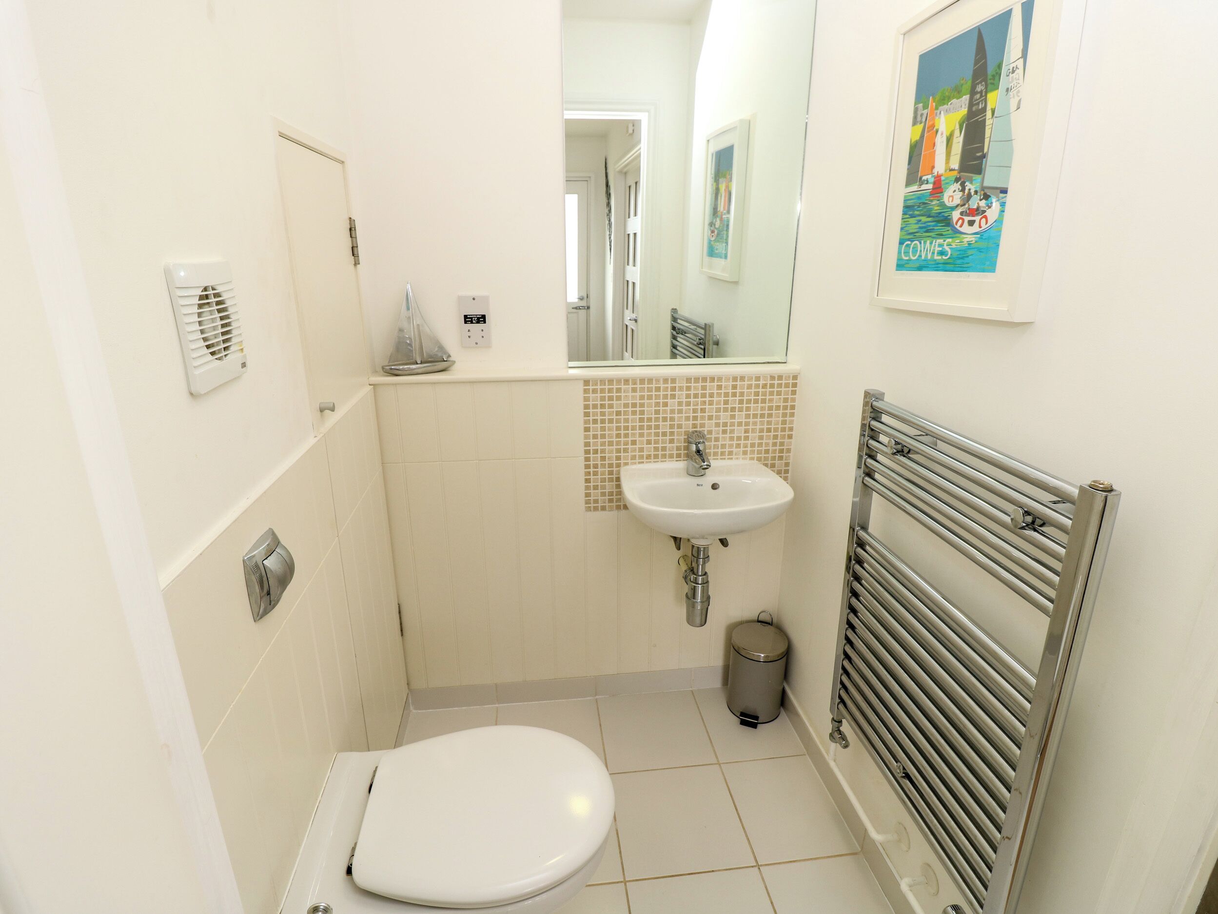 Une petite salle de bain propre, équipée de toilettes, d’un lavabo et d’un miroir.