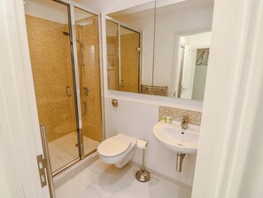 A bathroom with a glass shower enclosure, a toilet, and a sink. - Whitfield 16 (Yarmouth)