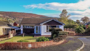 A single-story house with a sloped roof, a front porch, and a well-maintained lawn. - Green View (Llangollen)
