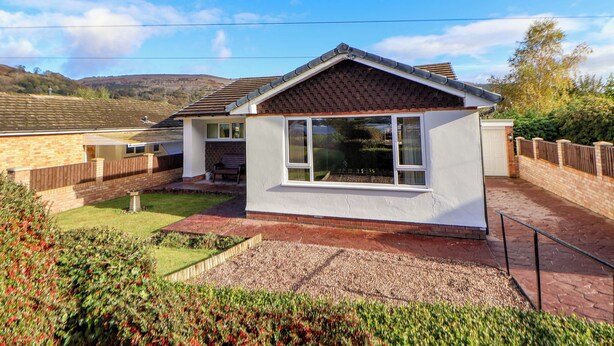 A single-story house with a tiled roof, a front porch, and a small garden area. - Green View (Llangollen)