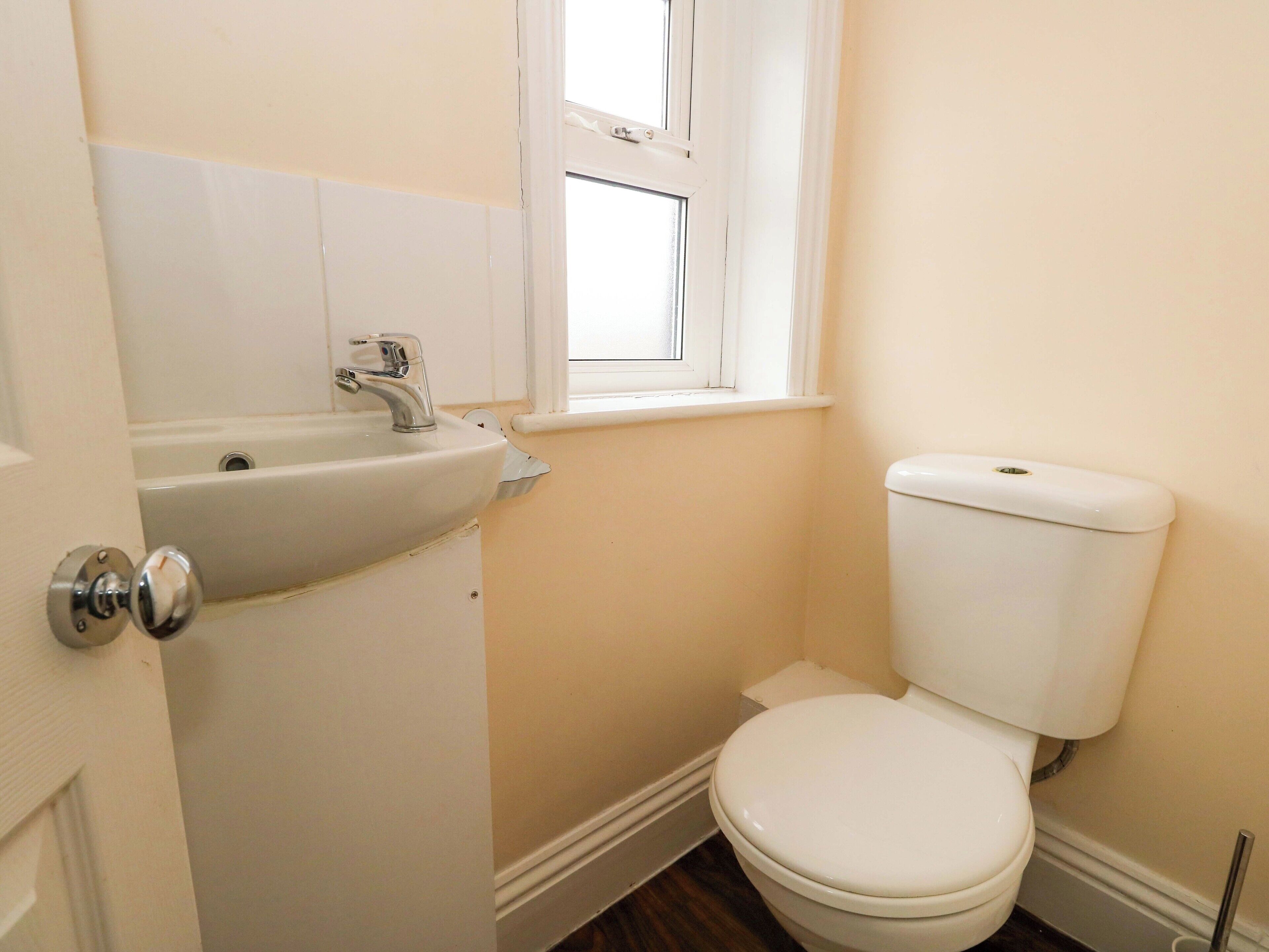 Une petite salle de bain avec un lavabo, des toilettes et une fenêtre.