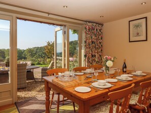 A dining area with a table set for four, large windows, and a view of the outdoors.