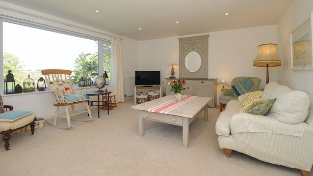 A living room with a sofa, a coffee table, a television, and a window with curtains. - Trestar (Wadebridge)