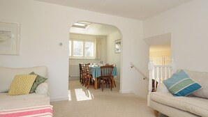 A living room with a sofa, a dining table with chairs, and a staircase leading to another level. - Trestar (Wadebridge)