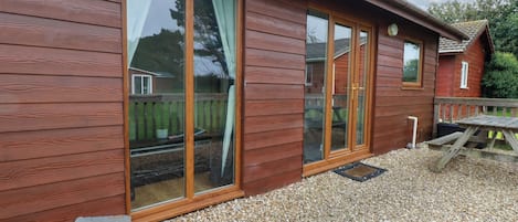 A wooden building with large sliding glass doors, a wooden deck, and a picnic table.