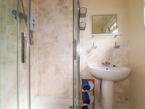 Ein Badezimmer mit einer Glaskabine zur Dusche, einem weißen Waschbecken und einem Spiegel darüber.