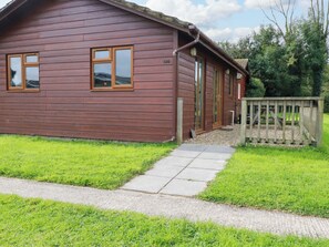 Eine Holzhütte mit Veranda, ein Kiesweg zum Eingang und einem Holzzaun.